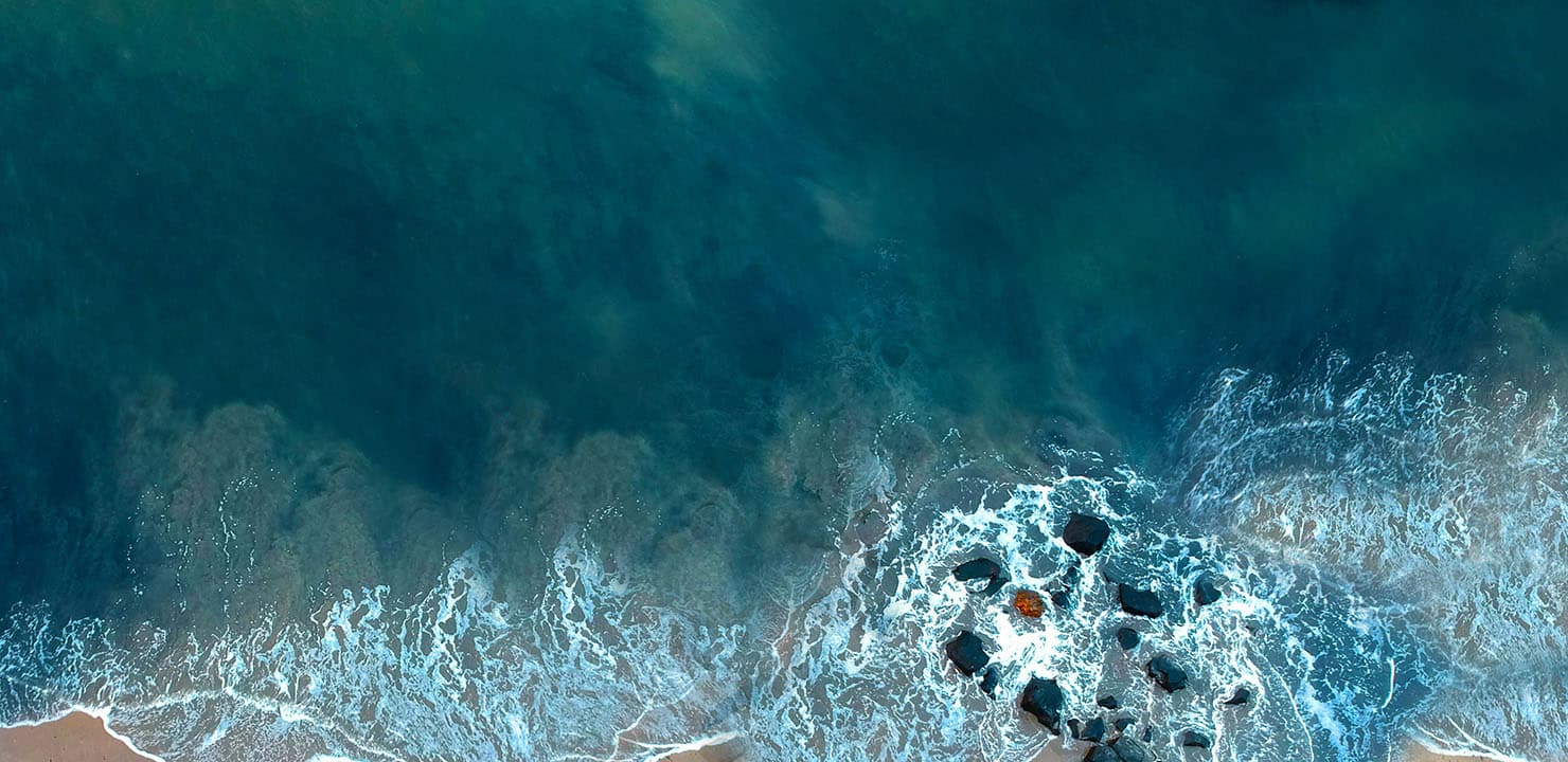 Aerial view of water breaking on rocks